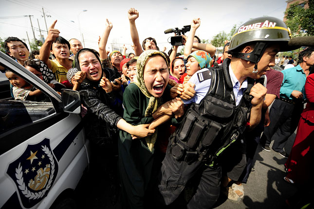 Ujgur asszonyok rángatnak egy kínai rohamrendőrt